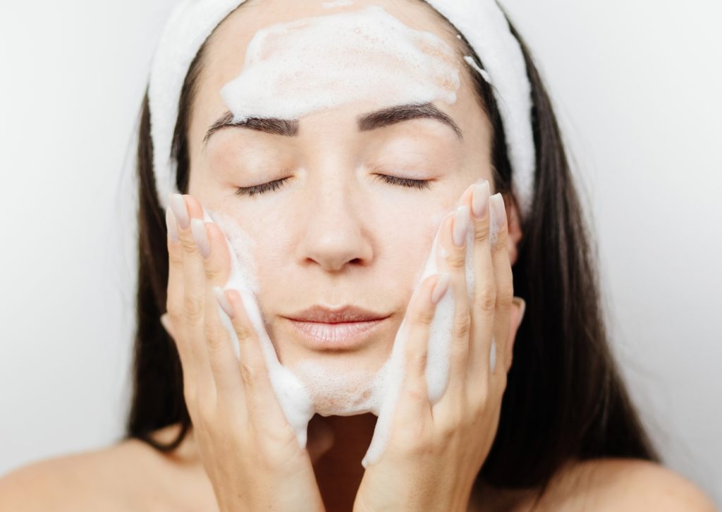 Vrouw reinigt haar gezicht met schuim
