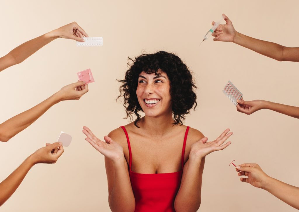 Lachende vrouw biedt verschillende soorten anticonceptie aan